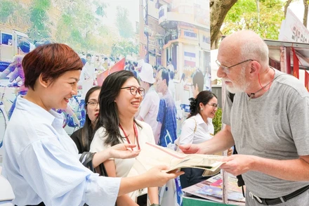 Du khách người nước ngoài trân trọng khi đón nhận tờ phụ san đặc biệt của Báo Nhân Dân.