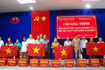 Tặng áo phao, cờ Tổ quốc và quà cho các gia đình ngư dân có hoàn cảnh khó khăn.