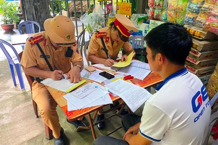 Cảnh sát giao thông Lào Cai lập biên bản xử phạt và tước giấy phép lái xe đối với tài xế và chủ doanh nghiệp "đội lốt" xe khách tuyến cố định. (Ảnh: QUỲNH TRANG)