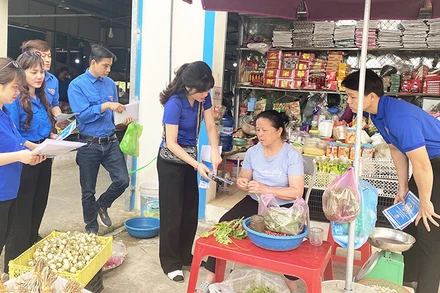 Ðoàn viên thanh niên Sở Thông tin và Truyền thông tỉnh Bắc Kạn hướng dẫn tiểu thương ở chợ sử dụng mã QR thanh toán trực tuyến. (Ảnh THU TRANG) 