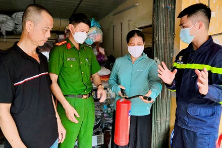 Cán bộ Cảnh sát PCCC và CNCH Công an huyện Thanh Trì, TP Hà Nội hướng dẫn tiểu thương chợ Yên Mỹ, huyện Thanh Trì sử dụng bình chữa cháy. (Ảnh HUY HOÀNG) 