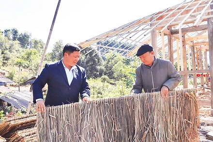 Già làng Cư Chừ Tú (bên phải) hướng dẫn người dân bản Tìa Ló B, xã Nong U, huyện Ðiện Biên Ðông, tỉnh Ðiện Biên làm nhà ở. 