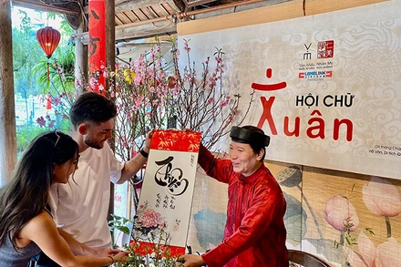 Một "thầy đồ" hiện đại trao bức thư pháp chữ quốc ngữ tặng du khách nước ngoài trong ngày đầu Xuân tại Văn Miếu-Quốc Tử Giám (Hà Nội). 