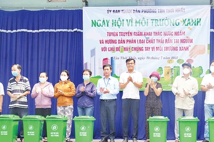 Ðại diện UBND phường Tân Thới Nhất (Quận 12) tặng thùng rác cho người dân. (Ảnh CTV)