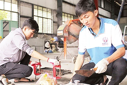 Từ nhiều thí nghiệm, Phạm Mạnh Ðình (bên phải) cùng cộng sự nghiên cứu thành công gạch tái chế từ rác thải nhựa. 