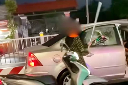 Bà T.T.B.L dùng 1 thanh kim loại đập vỡ kính và chèn ép 1 xe ô-tô đang chạy. (Ảnh: Công an cung cấp)