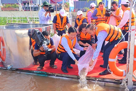 Đại biểu tham gia thả cá giống xuống sông Tiền với mục tiêu tái tạo nguồn lợi thủy sản.