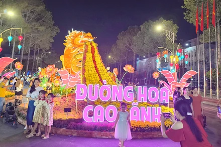 Du khách rất thích thú ngắm và chụp ảnh bên linh vật rồng, ngay đầu đường hoa. Ảnh: HỮU NGHĨA