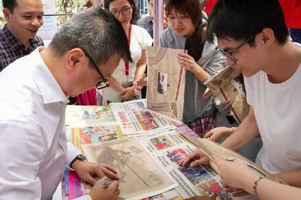 Tổng Biên tập Báo Nhân Dân trực tiếp phát báo và ký tặng bạn đọc tại không gian Triển lãm.