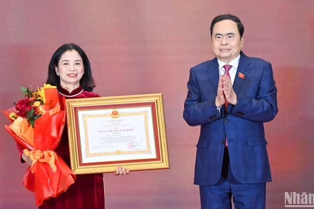 Chủ tịch Quốc hội Trần Thanh Mẫn trao Huân chương Lao động hạng Nhất và tặng hoa chúc mừng đồng chí Lê Thị Nguyệt.