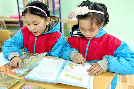Các em học sinh đọc sách tại thư viện của Trường Phổ thông dân tộc bán trú Tiểu học Ngam La. (Ảnh NFVC)