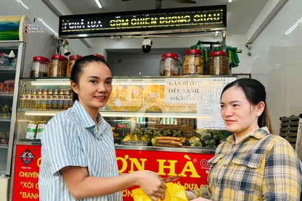 Hộ gia đình chị Phạm Tuyết Linh (bên trái), cơ sở sản xuất bánh mì và chả lụa Sơn Hà nổi tiếng hơn 40 năm qua tại Bạc Liêu ký cam kết với cơ quan chức năng thực hiện nghiêm các biện pháp an toàn thực phẩm trong dịp Tết. (Ảnh: TRỌNG DUY)