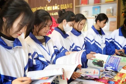 Các em học sinh đọc sách tại gian trưng bày chào mừng 50 năm Ngày Giải phóng miền nam, thống nhất đất nước tại Thư viện Bắc Giang.