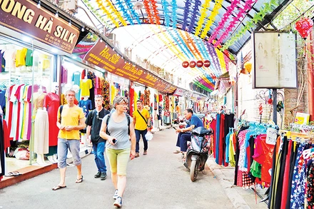 Khách du lịch tham quan quầy hàng trong làng dệt lụa Vạn Phúc.