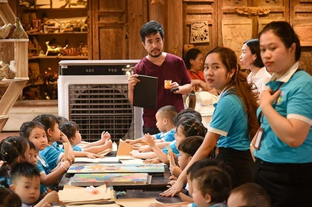 Nghệ nhân Nguyễn Tấn Phát hướng dẫn các em nhỏ thực hành làm tranh in khắc gỗ.