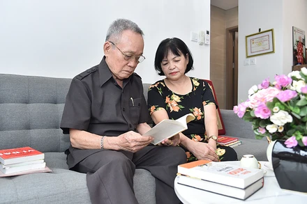 Thượng tá, cựu chiến binh Tạ Minh Thanh (bên trái) xem lại kỷ vật thời chiến. (Ảnh THỦY NGUYÊN)