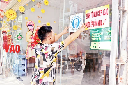 Nhân viên một cơ sở du lịch ở Đà Nẵng dán biểu tượng xã hội hóa nhà vệ sinh công cộng tại khu vực dễ thấy. (Ảnh Thanh Tâm)