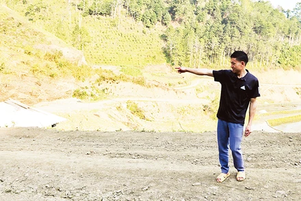 Triệu Tòn Lai chỉ về phía diện tích đất gia đình anh hiến để thực hiện chương trình xây dựng nông thôn mới. (Ảnh NGUYỄN NGHĨA)