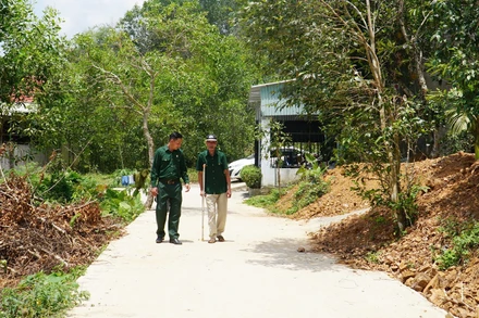 Hai cha con ông Bùi Văn Tượng đi trên con đường mới từ một phần đất gia đình đóng góp.