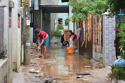 Người dân dọn dẹp bùn đất sau trận lụt.