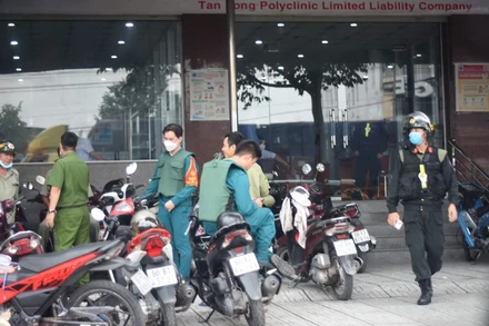 Lực lượng chức năng bao vây bên ngoài một phòng khám, chữa bệnh để phục vụ việc khám xét.