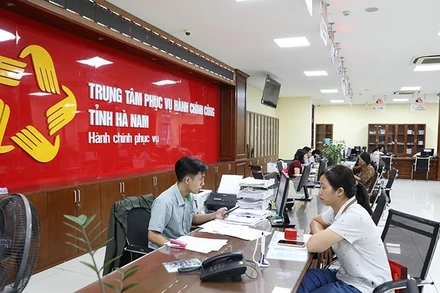Cán bộ, công chức Trung tâm hành chính công tỉnh Hà Nam giải quyết thủ tục hành chính cho người dân. (Ảnh ĐÀO PHƯƠNG)