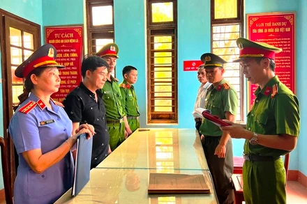 Nguyễn Quốc Trung, Giám đốc Công ty TNHH Thạch Phú Hưng (áo đen, thứ 2 từ trái sang) nghe đọc lệnh khởi tố. (Ảnh: Công an cung cấp)