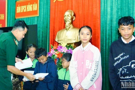 Đại diện Đồn Biên phòng Cửa khẩu Hồng Vân trao kinh phí hỗ trợ cho các em học sinh. (Ảnh: Võ Tiến).