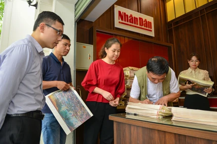 Họa sĩ Nguyễn Văn Mạc - trưởng nhóm tác giả bức panorama “Chiến dịch Điện Biên Phủ” ký tặng độc giả Báo Nhân Dân.
