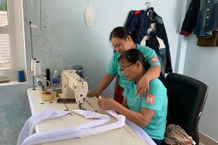 Cô Thanh (ngồi) tỉ mỉ hướng dẫn Linh gấp nếp vải.