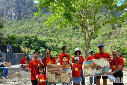 Du khách mang theo phụ san của Báo Nhân Dân về Chiến dịch Hồ Chí Minh, check-in tại thác Bản Giốc, xã Đàm Thủy, huyện Trùng Khánh, tỉnh Cao Bằng.