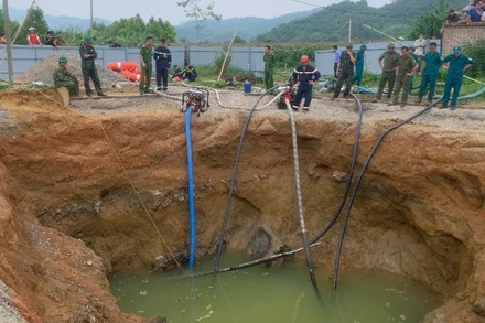 Dùng máy bơm hút nước để tìm kiếm nạn nhân. (Ảnh: TUẤN SƠN)