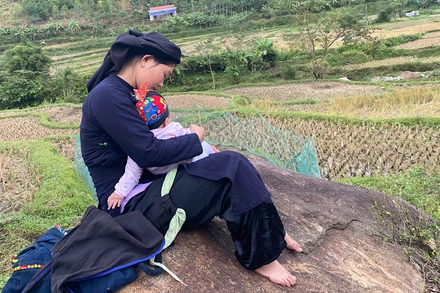 Những đứa trẻ được nghe mẹ hát ru khi theo mẹ đi làm. (Trong ảnh: Một phụ nữ ở xã Giáo Hiệu hát ru trẻ khi đi làm đồng). (Ảnh: THU TRANG)