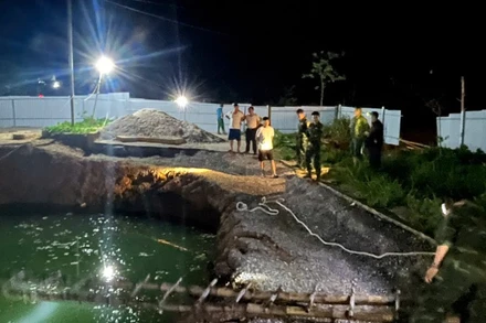 Lực lượng chức năng và người dân tìm kiếm tại khu vực hố sụt trong đêm 26/7. (Ảnh: TUẤN SƠN).