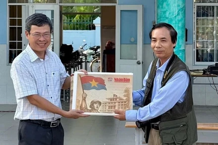 Nhà báo Trọng Duy, đại diện Văn phòng Báo Nhân Dân tại Bạc Liêu trao Phụ san đặc biệt của Báo Nhân Dân đến thầy giáo Dương Bình, Bí thư Chi bộ, Hiệu trưởng Trường Trung học phổ thông Chuyên Bạc Liêu.