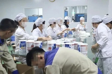 Công nhân đóng hộp thành phẩm tại cơ sở sản xuất sữa bột giả quy mô lớn vừa bị Công an thành phố Hà Nội triệt phá. (Ảnh: Báo Công an nhân dân) 
