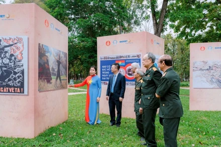 Họa sĩ Nguyễn Thu Thủy giới thiệu tác phẩm tới các cựu chiến binh tham quan triển lãm. (Ảnh: AN HẢI)