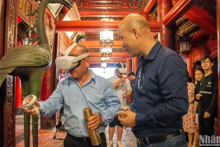 Khách du lịch trải nghiệm viết thư pháp bằng công nghệ thực tế ảo tại Văn Miếu-Quốc Tử Giám. (Ảnh: HÀ NAM)