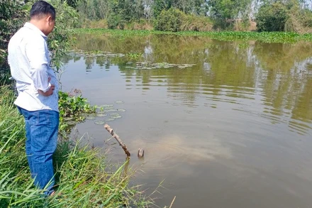 Người dân kiểm tra một miệng cống ra kênh, khu vực nguồn nước bị ô nhiễm.