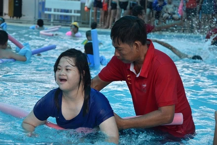 Các em khuyết tật được các thầy hướng dẫn dạy tập làm quen với nước.