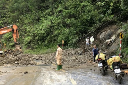 Lực lượng Cảnh sát giao thông cùng lực lượng chức năng khắc phục một điểm sạt lở trên Quốc lộ 32. Ảnh: Thái Sơn