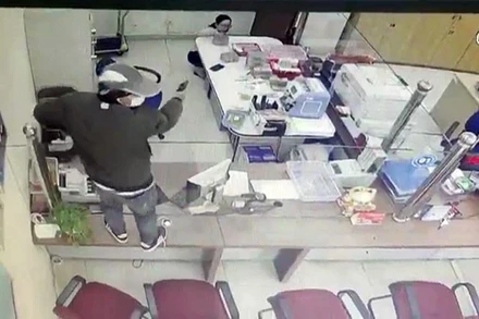 Đối tượng chĩa súng vào nhân viên ngân hàng yêu cầu bỏ tiền vào ba-lô. 