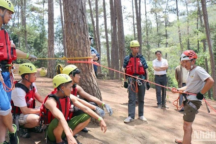 Kỹ thuật viên hướng dẫn du khách trước khi tham gia du lịch mạo hiểm đu dây vượt thác.