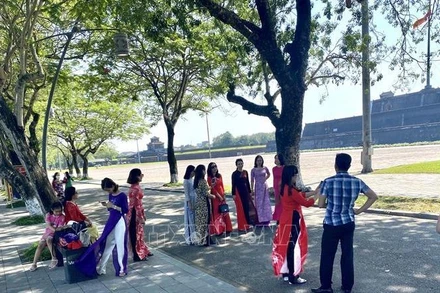 Khách du lịch mặc áo dài tham quan Khu di tích cố đô Huế. (Ảnh: TTXVN)