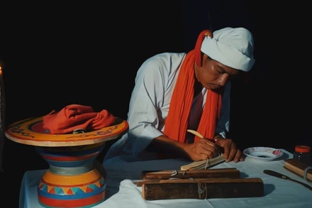 Phó Cả sư Nại Cao Liêm đang thực hiện công đoạn khắc chữ trên lá buông. (Ảnh: NGỌC XIÊM)