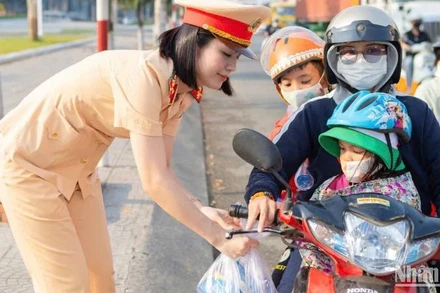 Cán bộ, chiến sĩ Phòng Cảnh sát giao thông Công an tỉnh Đồng Nai phát nước suối, khăn lạnh hỗ trợ người dân về quê đón Tết trên Quốc lộ 1A.