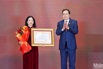 Chủ tịch Quốc hội Trần Thanh Mẫn trao Huân chương Lao động hạng Nhất và tặng hoa chúc mừng đồng chí Lê Thị Nguyệt. (Ảnh: Duy Linh)