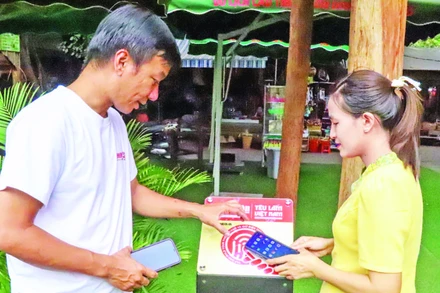 Du khách quét bảng gắn chip NFC Dự án “Yêu lắm Việt Nam” tại Trung tâm du lịch cầu treo Buôn Đôn, tỉnh Đắk Lắk. (Ảnh: KIM BẢO)