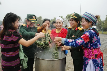 Đồng bào các dân tộc đang hoạt động tại "Làng" cùng các chiến sĩ tham gia luộc bánh chưng. (Ảnh: PH)