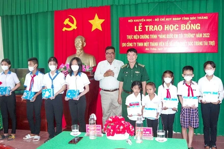 Đại diện Bộ đội Biên phòng tỉnh và Hội khuyến học tỉnh Sóc Trăng trao học bổng cho các em học sinh. (Ảnh: VĂN LONG)